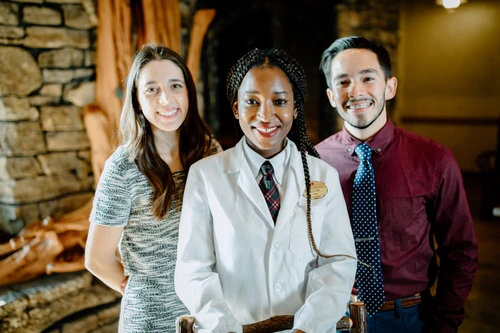 Three people standing smiling.