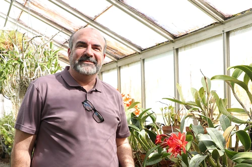 Man smiling next to Orchids 