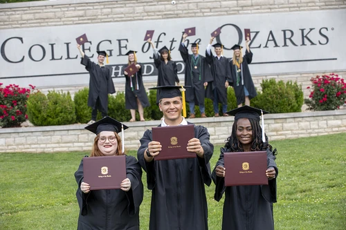 Group of students in caps and gowns smiling.