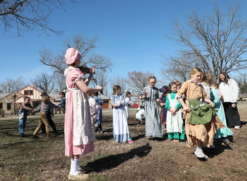 Guest plays fiddle for students at recess. 