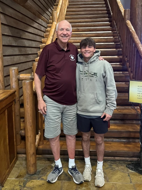 A tall man is standing next to a male student in the lodge area at the Keeter Center