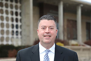 Man smiling in front of academic building