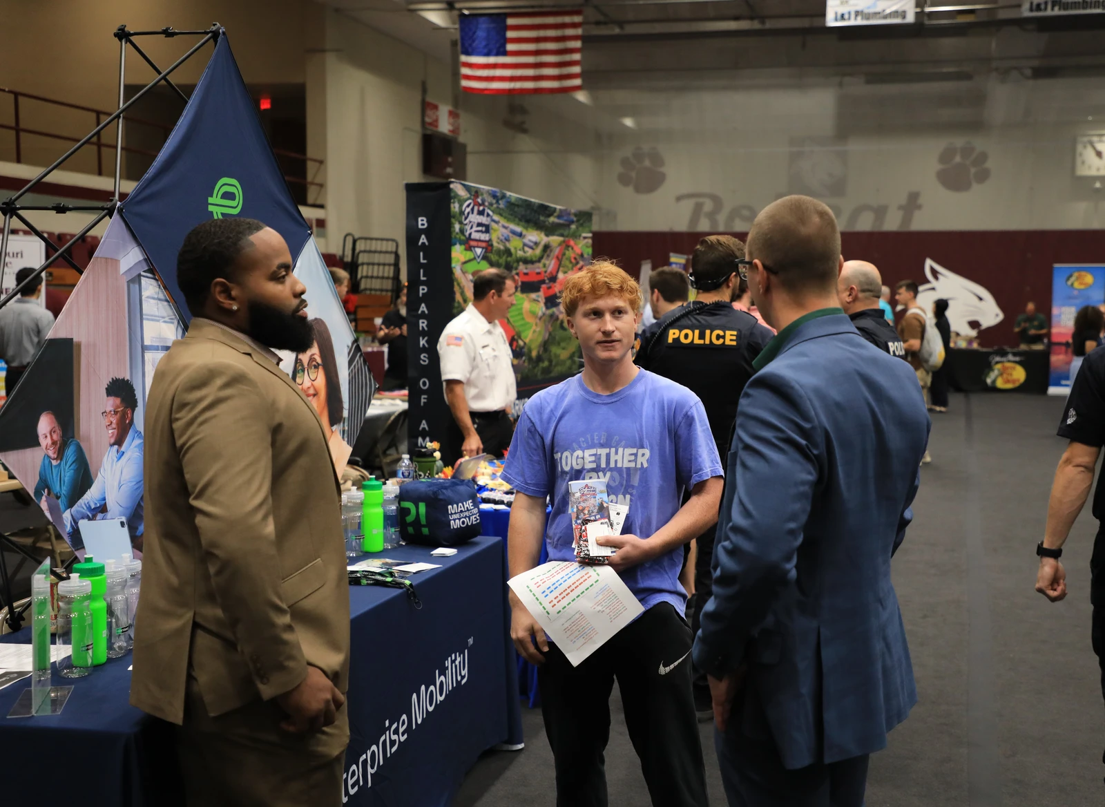 This image depicts three men speaking to each other during a career fair.  