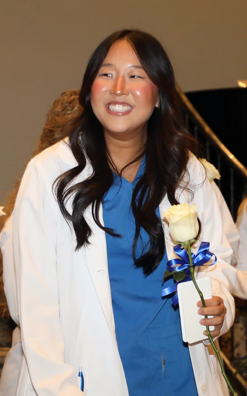 Student smiling holding rose.