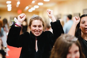 Girl with a crown and fuzzy jacket walked down the red carpet at Night to Shine. 