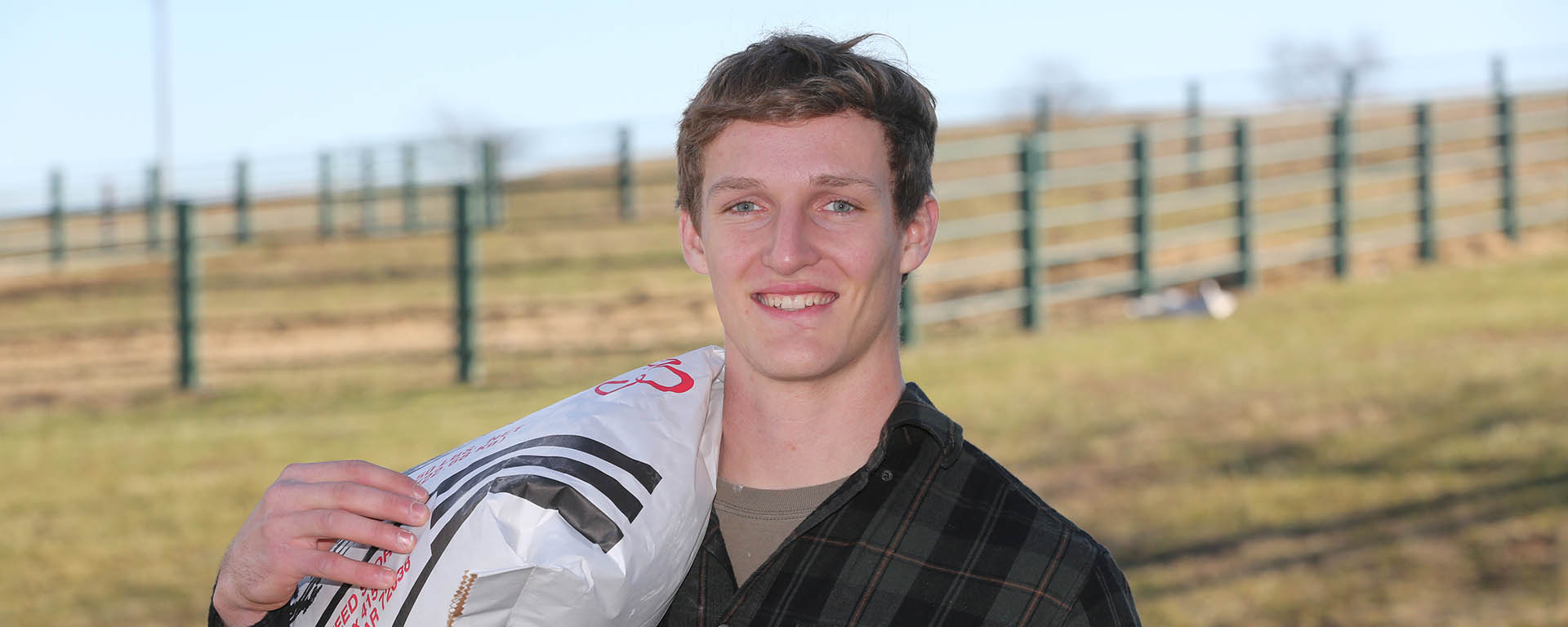 Student on College farm carrying a bag of feed