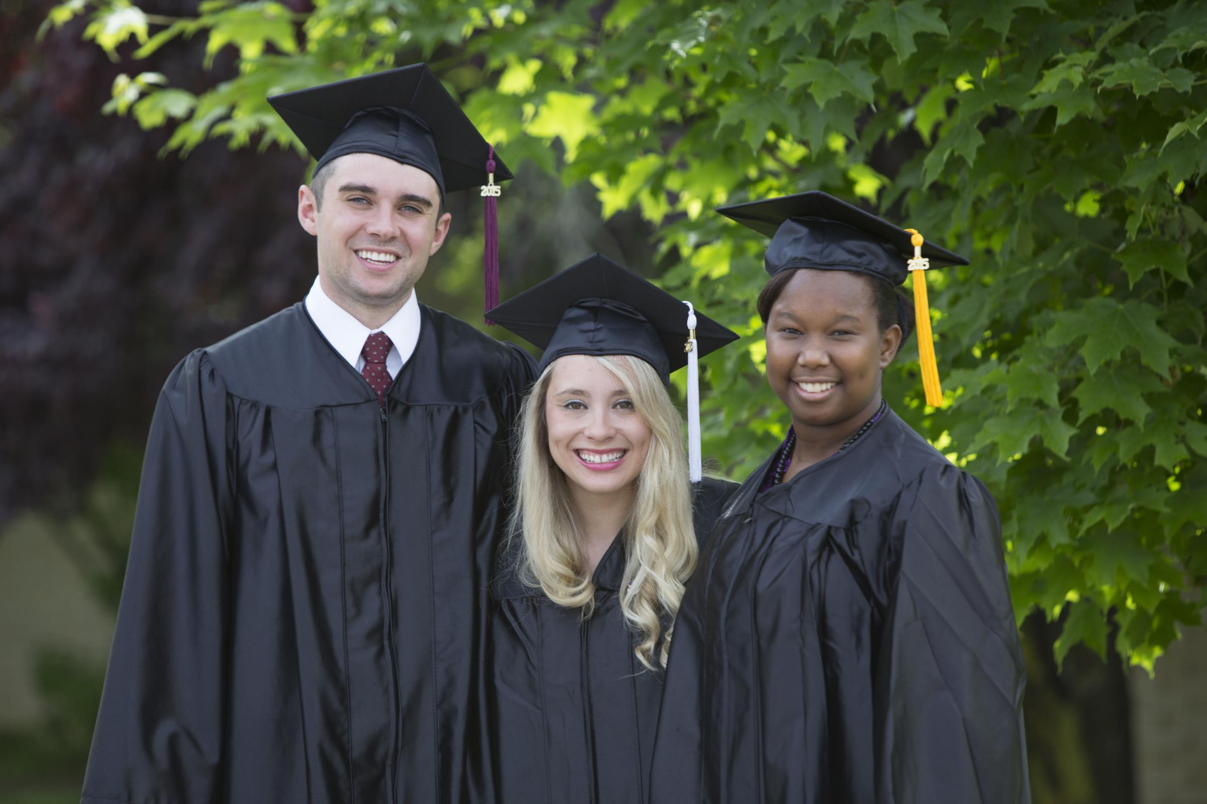 Three graduates pose in their regalia.