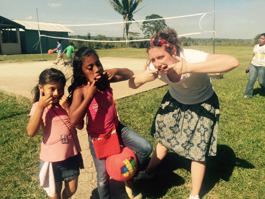 Missionary student making silly faces with young children.
