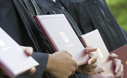 Graduates holding diploma covers.