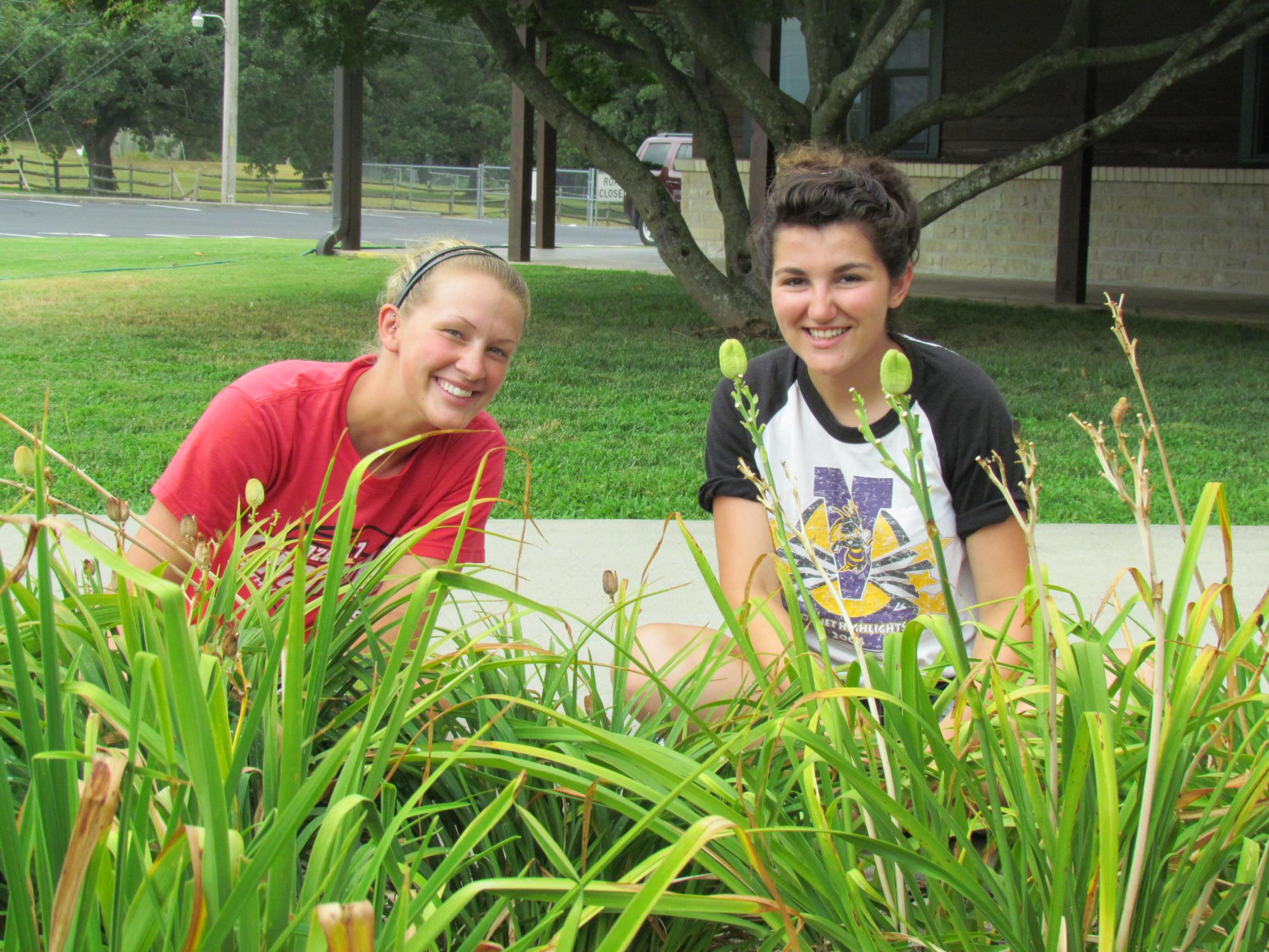 Two students smiling while planting flowers