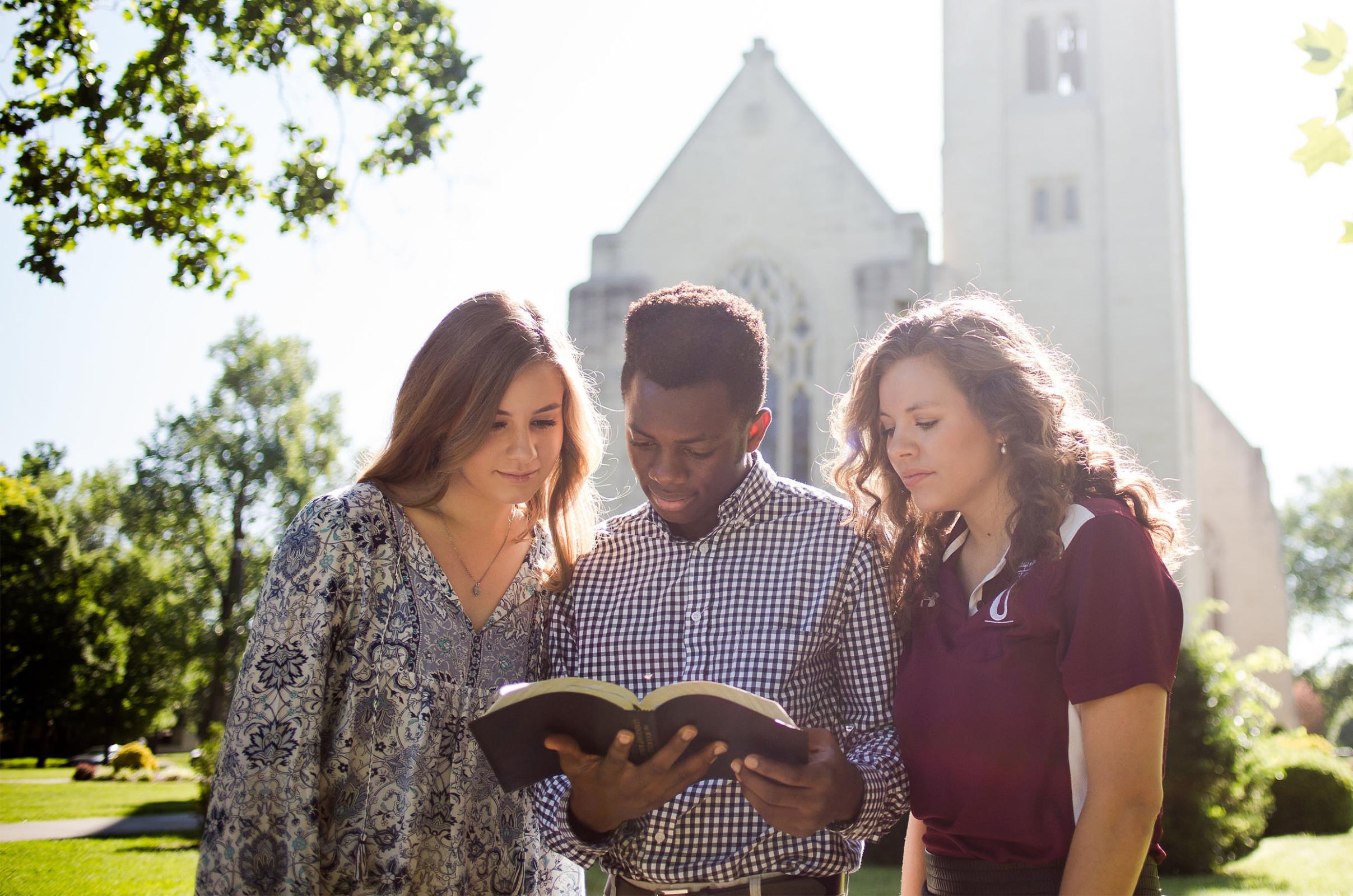 3 students reading the Bible outside of the chapel