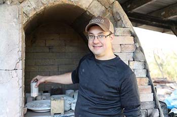 College of the Ozarks assistant professor of art places pottery inside the kiln