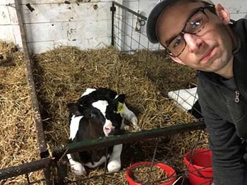 Paul Baker, admissions and recruitment coordinator, volunteers in the calf barn. Currently, 11 calves have to be bottle fed. Baker, who has no previous farm experience, and other interim dairy workers maintain the free-stall barn, feed the bottle calves, and clean the milking parlor.