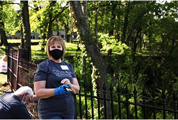 Alumna Sandy Cooper paints a fence by the College’s Scripture Garden on Doc Good Day.