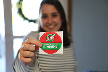 Student holds logo of Operation Christmas Child during annual donation drive at College of the Ozarks.